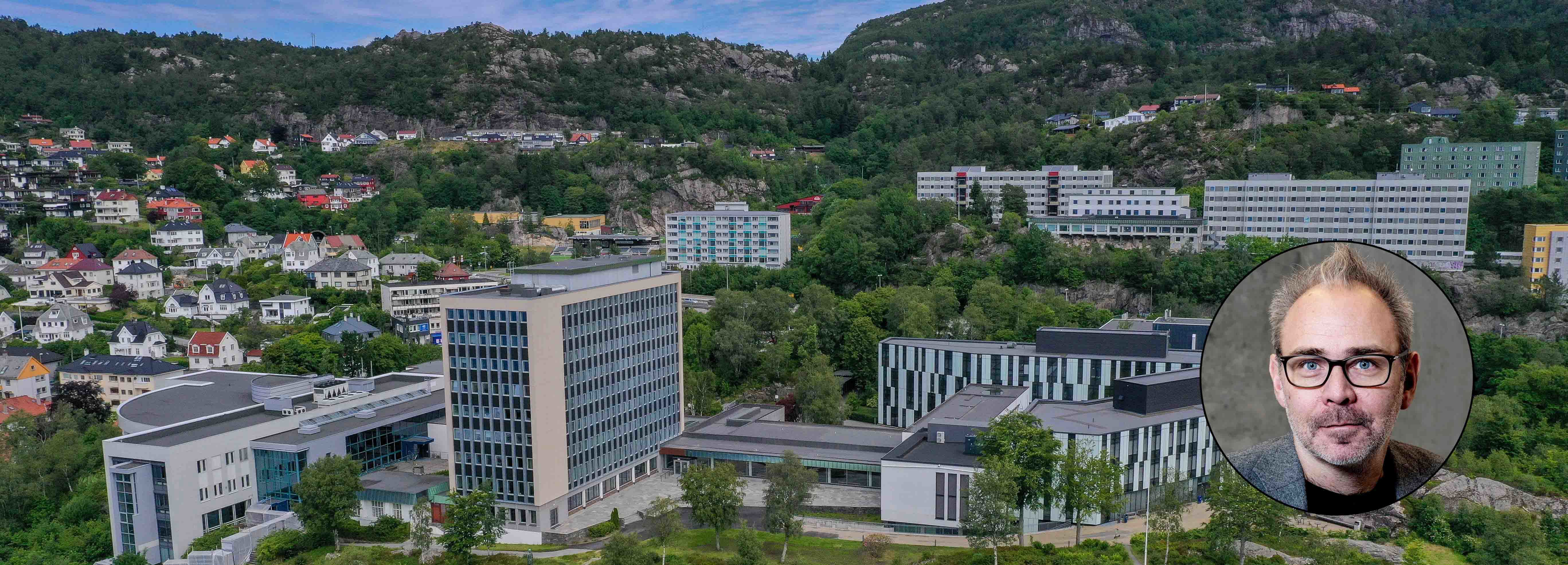 Oversiktsbilde av NHH sitt campus i Bergen med moderne skolebygg i en grønn åsside. Et sirkulært portrettbilde av rektor Helge Thorbjørnsen er lagt over bildet i det nedre høyre hjørnet. Foto_helge skodvin
