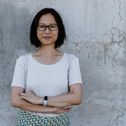 A portrait photo of Associate Professor Annelise Ly against a grey brick wall.