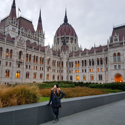 A girl in black clothes stands in front of the Parliament building in Budapest, Hungary.