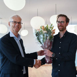 Eirik recieving flowers from Rector Øystein Thøgersen. Photo: NHH