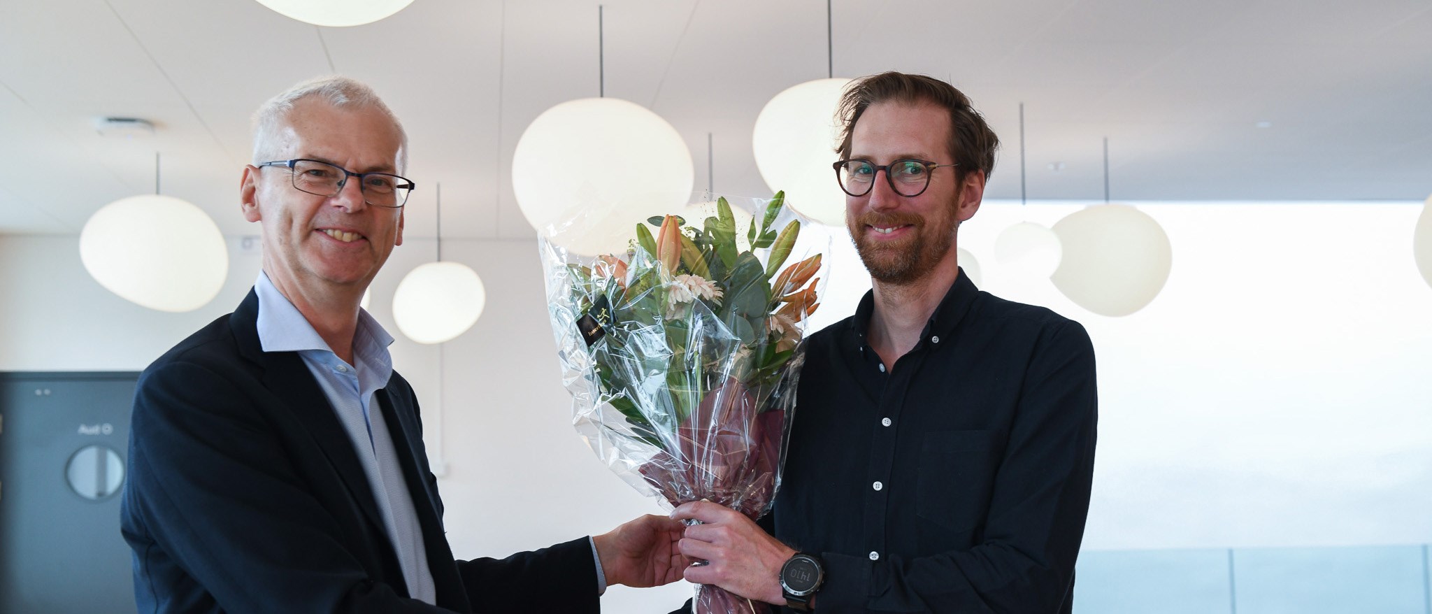 Eirik recieving flowers from Rector Øystein Thøgersen. Photo: NHH