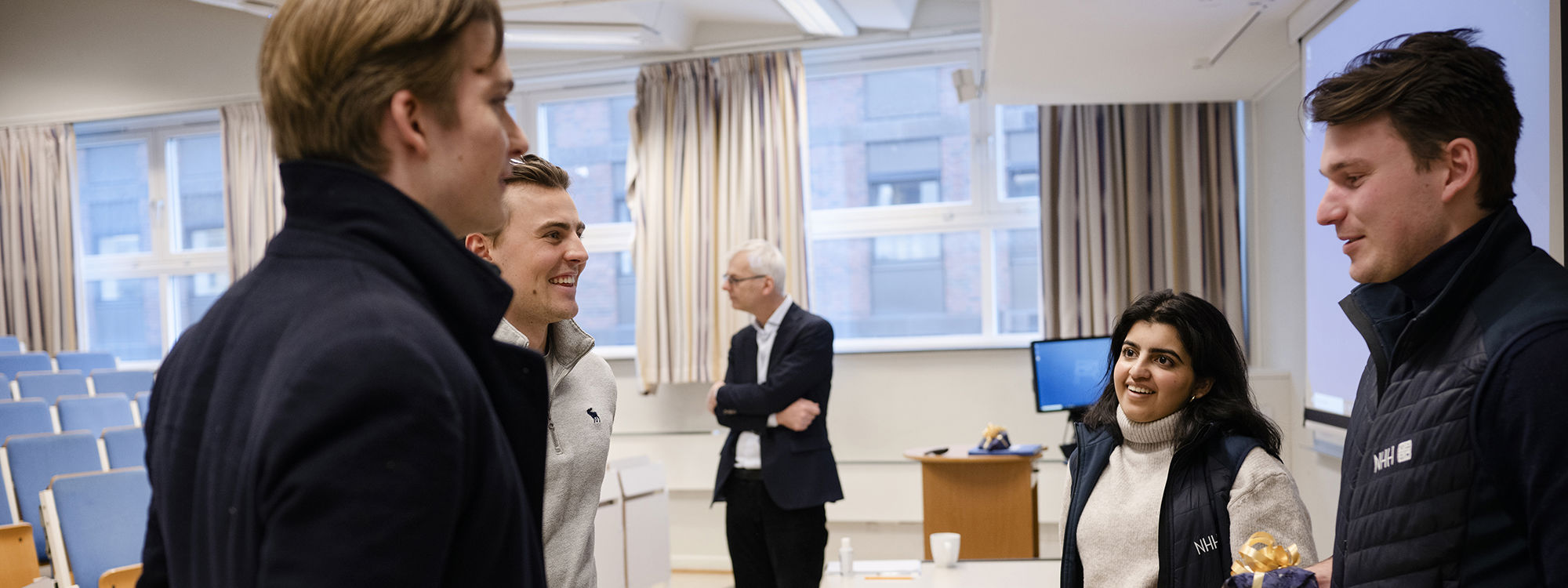  Bilde av elever ved Oslo Handelsgymnasium som snakker med Mah Noor Munir og Eirik Aarthun.