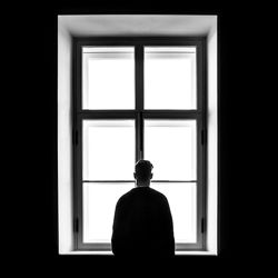 Person standing at window alone. Photo: Sasha Freemind/Unsplash