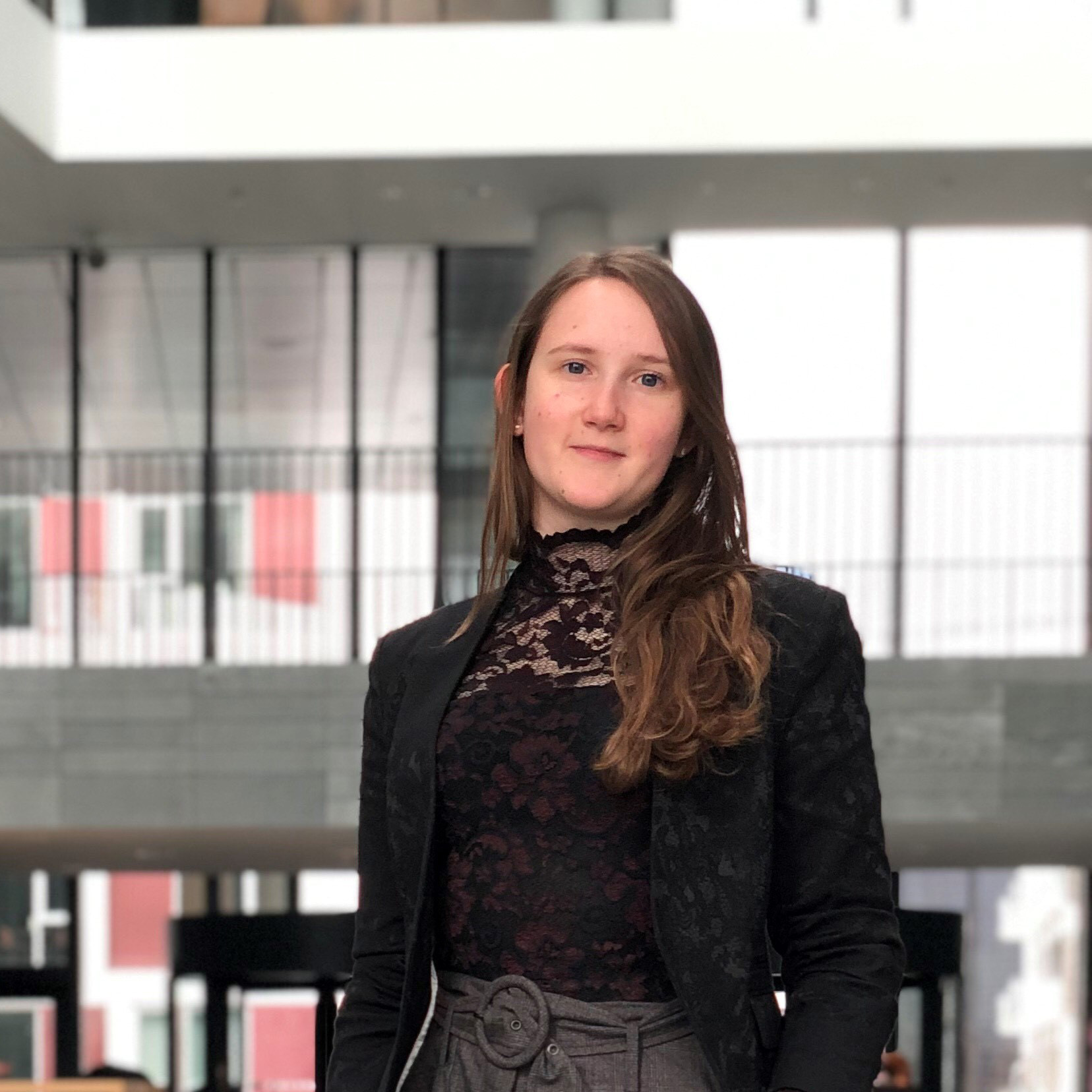 Portrettbilde av en ung dame med mørkt langt hår og blå øyne som ser rett i kamera. 